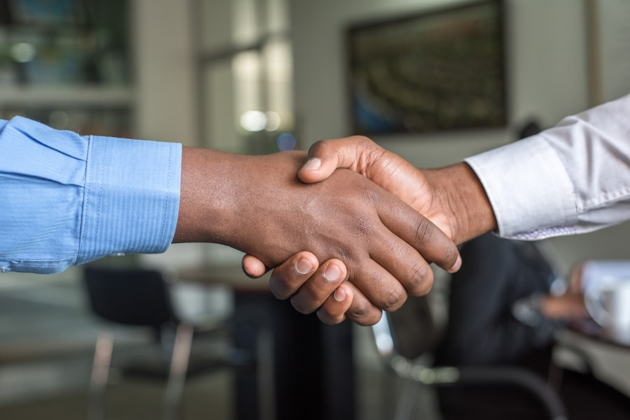 Two professionals in suits shaking hands in an office